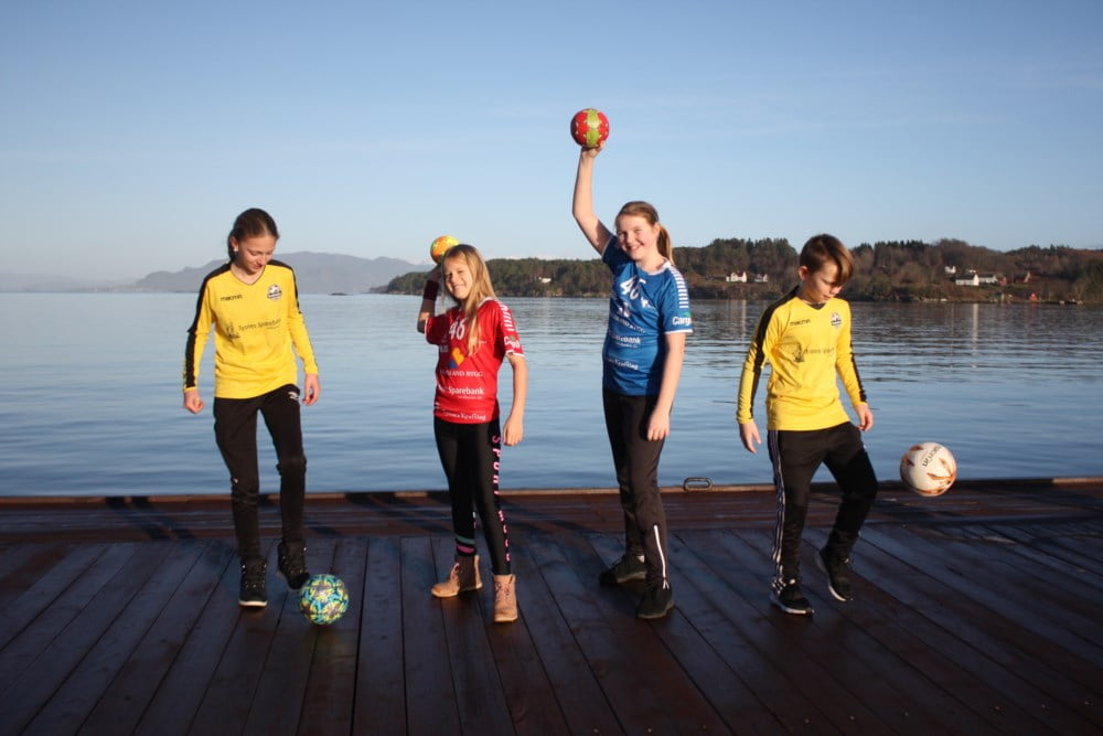 Unger på kaia i Våge med idrettsdrakter på og fotballer og håndballer med